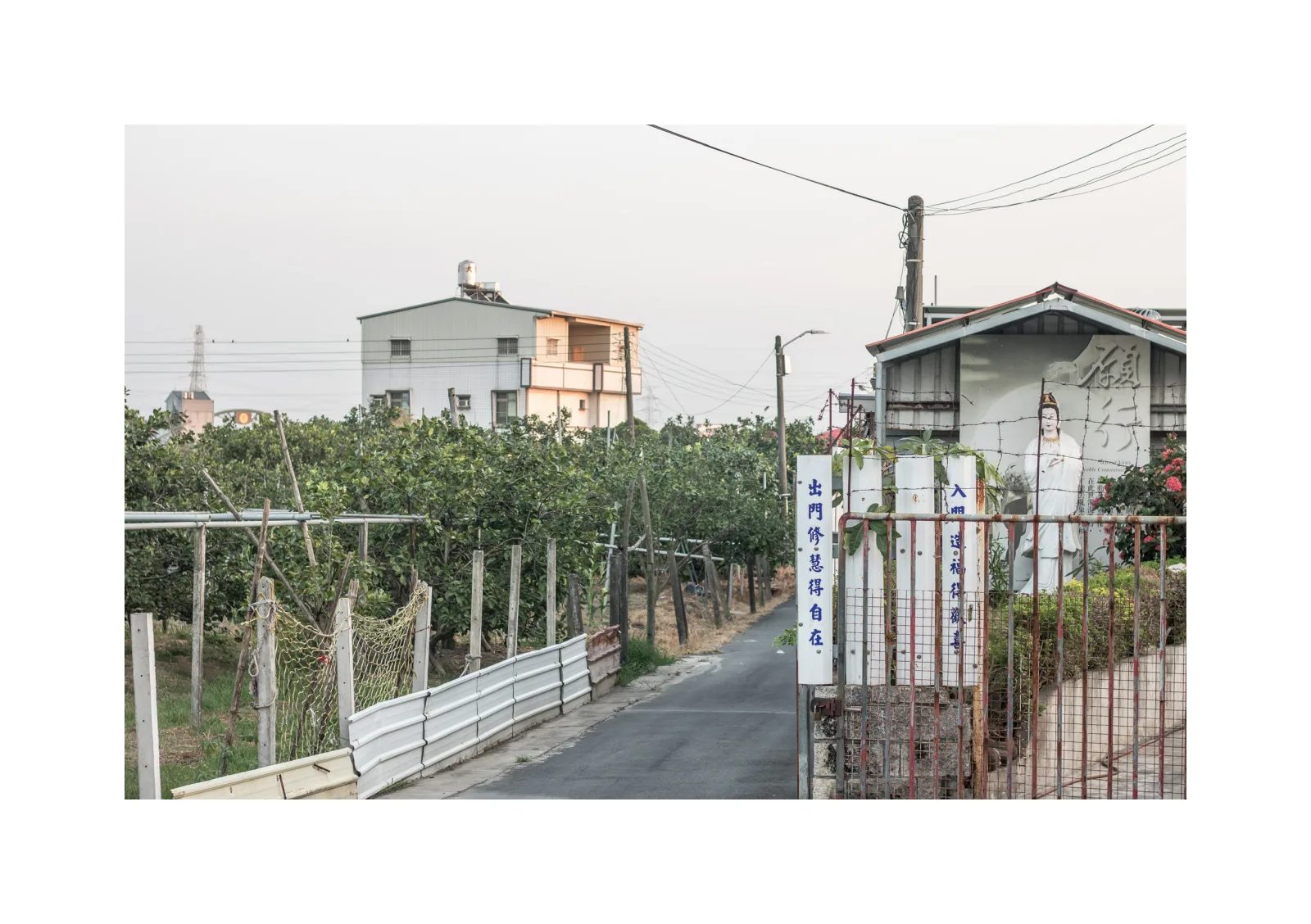 小冊子《1》第 18 頁：小路從果園與房屋之間延伸，圍欄旁豎立著直式標牌。
