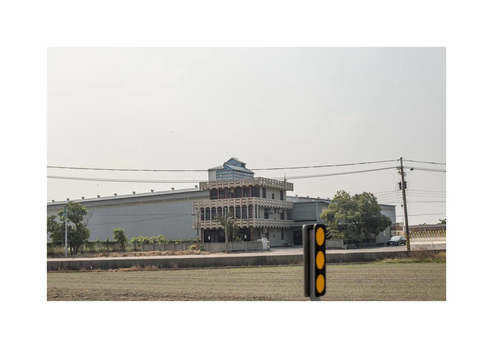 小冊子《1》第 30 頁：空曠田地後方是一座多層裝飾性建築，前方有電線與道路標記。